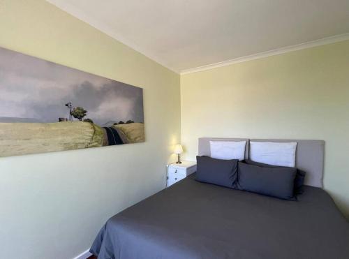 a bedroom with a bed and a painting on the wall at Harbour Cottage Kalk Bay in Cape Town