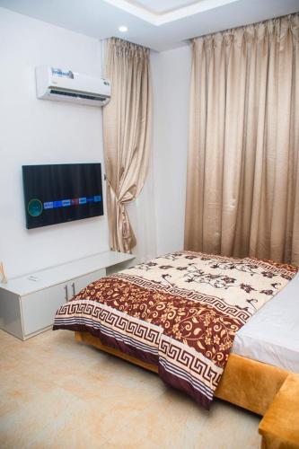 a bedroom with a bed and a flat screen tv at willy's apartment in Lagos