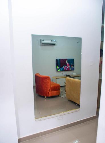 a mirror reflecting a room with a chair and a television at willy's apartment in Lagos