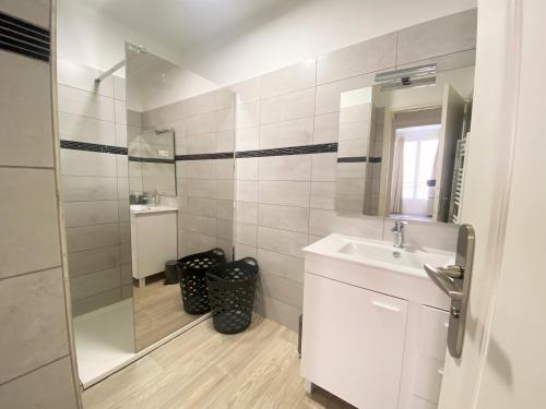 une salle de bain blanche avec un lavabo et un miroir dans l'établissement Appartement Sacré Coeur 6 couchages AJACCIO, à Ajaccio
