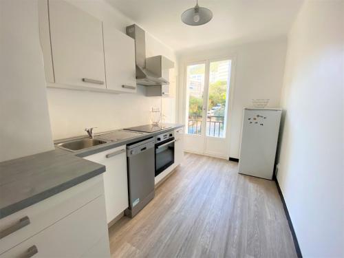 une cuisine avec des armoires blanches et un réfrigérateur en acier inoxydable dans l'établissement Appartement Sacré Coeur 6 couchages AJACCIO, à Ajaccio