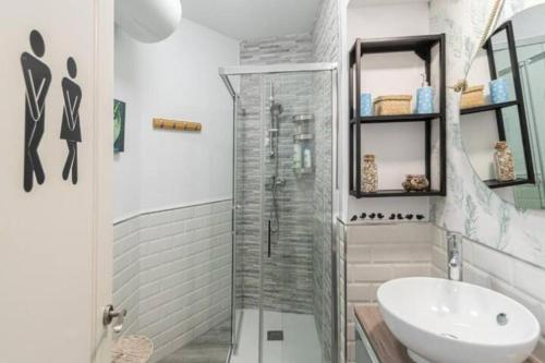 La salle de bains blanche est pourvue d'une douche et d'un lavabo. dans l'établissement El Sueño de Cádiz by Gades Gestión, à Cadix
