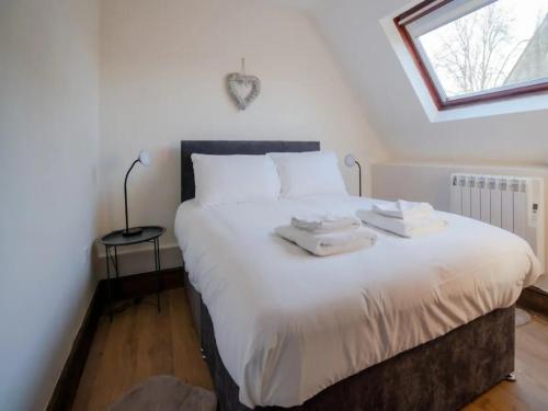 um quarto com uma grande cama branca com duas toalhas em Pass the Keys Converted 17th century barn with garden parking em Cheltenham