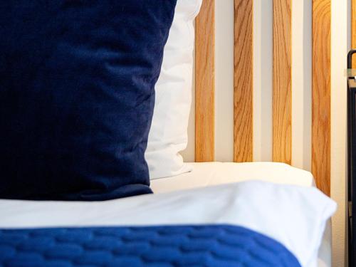 a close up of a bed with a blue and white pillow at Hotel Britannia in Esbjerg