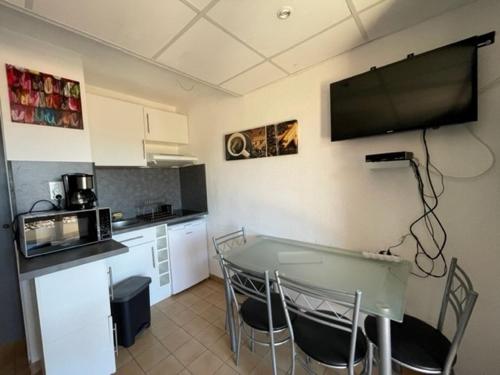 une cuisine avec une table et une télévision murale dans l'établissement Villa Bella Vista, Santa Giulia, à Porto-Vecchio