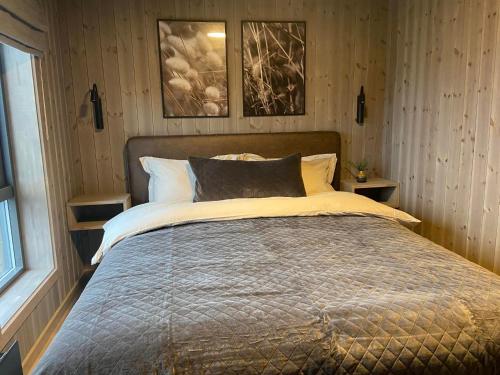 łóżko w sypialni z dwoma zdjęciami na ścianie w obiekcie Hjortehytte w mieście Åfarnes