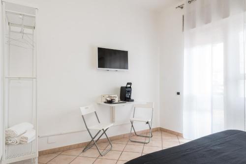 a white bedroom with a desk and two chairs at Travelershome 7Metri GuestHouse in Ciampino