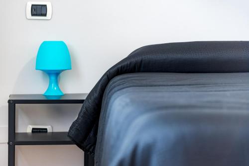 a bed with a blue lamp on a night stand at Travelershome 7Metri GuestHouse in Ciampino