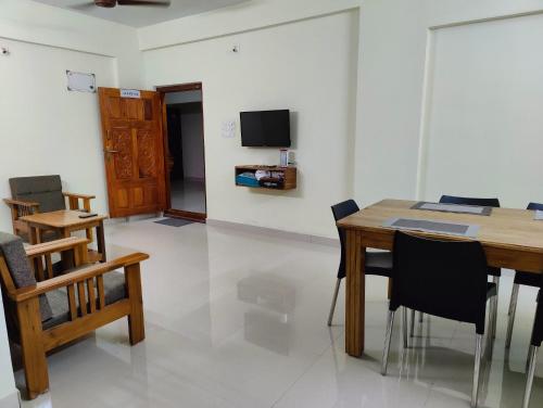 a dining room with a table and chairs and a tv at Sri Vidya Palace in Udupi
