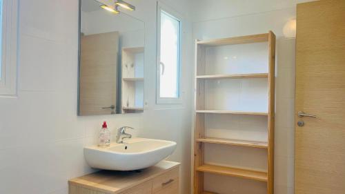 La salle de bains est pourvue d'un lavabo, d'un miroir et d'étagères. dans l'établissement Appartement Le Domaine L'ILE ROUSSE, à LʼÎle-Rousse