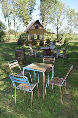 un gruppo di sedie, un tavolo da picnic e una casa di La Bivouac a Nort-sur-Erdre