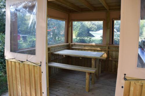 a wooden porch with a bench and two windows at La Bivouac in Nort-sur-Erdre