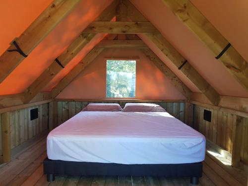 a bed in a room with a roof at La Bivouac in Nort-sur-Erdre