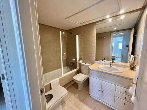ein Badezimmer mit einem Waschbecken, einem WC und einem Spiegel in der Unterkunft Puerto Banús, seaviews, 2 bedrooms and parking in Marbella
