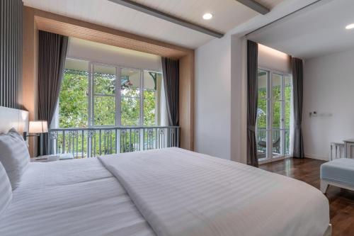 a bedroom with a white bed and a balcony at Na Sook Wellness Resort in Ao Nam Mao