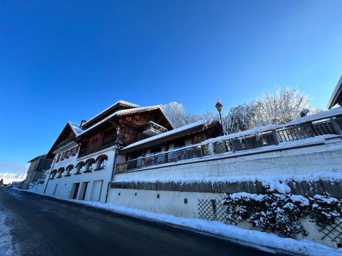 a building with snow on the side of a street at Hôtel le Jalouvre in Mont-Saxonnex