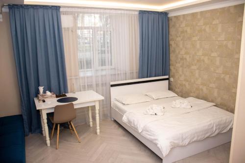 Schlafzimmer mit einem Bett, einem Schreibtisch und einem Fenster in der Unterkunft AG Hotel in Almaty