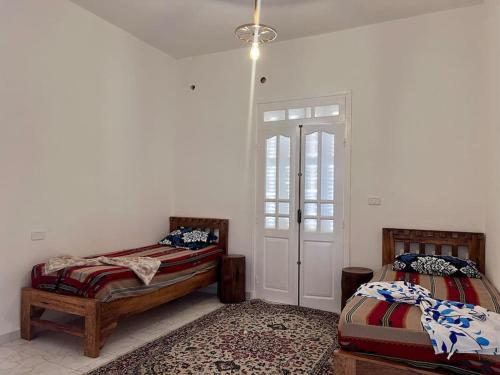 a bedroom with two beds and a door in it at Dar Zakaria Toursitic Area in Tozeur
