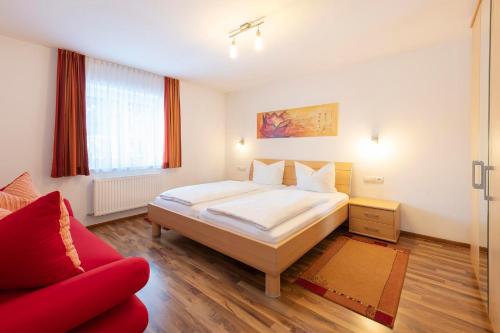 a bedroom with a large bed and a red couch at Gästehaus Sahin in Bartholomäberg