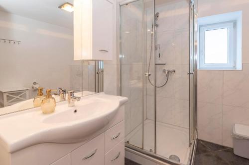biała łazienka z umywalką i prysznicem w obiekcie Gästehaus Sahin w mieście Bartholomäberg