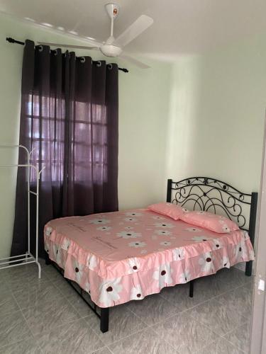 a bedroom with a pink bed with a black curtain at D'Batu Hampar Homestay R2 