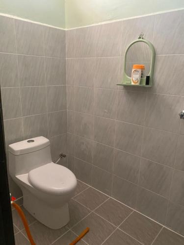 a bathroom with a toilet and a tile wall at D'Batu Hampar Homestay R2 