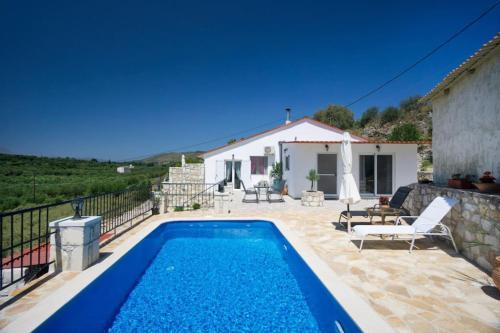 a villa with a swimming pool in front of a house at Levanda Villas - Country villas with private pool in Exopoli