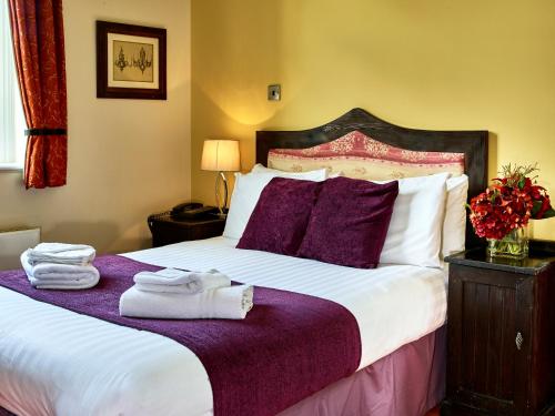 a hotel room with a bed with towels on it at Hitchin Priory Hotel in Hitchin