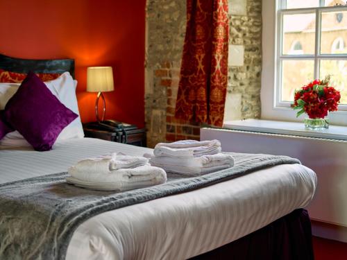 a hotel room with a bed with towels on it at Hitchin Priory Hotel in Hitchin