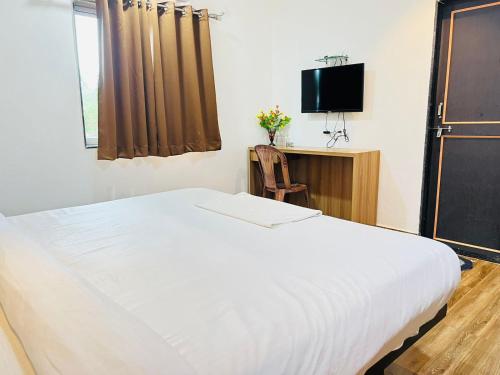 1 dormitorio con 1 cama blanca grande y TV en Hotel Karna Residency , Ranjangaon, en Ranjangaon