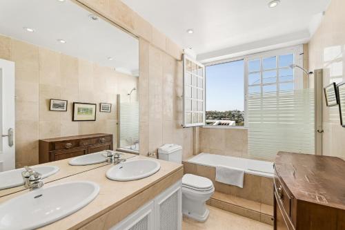 y baño con 2 lavabos, bañera y aseo. en Spacy stylish Aloha townhouse, en Marbella