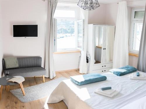 a white bedroom with a bed and a chair at Studio A in Dubrovnik