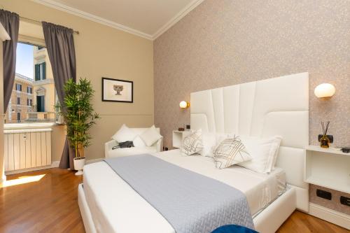 um quarto branco com uma grande cama branca com almofadas em 52 Vespasiano Vatican Suites em Roma