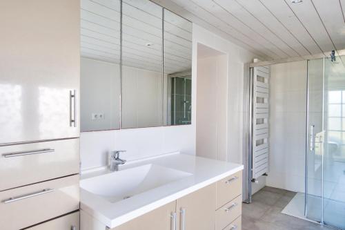 ein weißes Bad mit einem Waschbecken und einer Dusche in der Unterkunft Douce parenthese en Vendee in Saint-Michel-en-lʼHerm