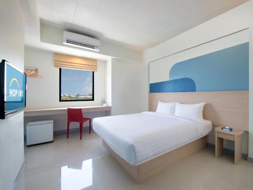 a bedroom with a white bed and a red chair at Hop Inn Suphanburi in Suphan Buri