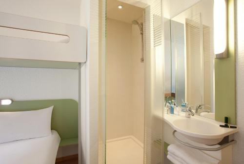 La salle de bains est pourvue d'un lavabo, de toilettes et d'un miroir. dans l'établissement ibis budget Tours Nord, à Tours