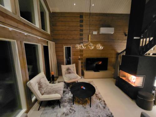 a living room with a fireplace and a table and chairs at Villa Sol Del Luosto in Luosto