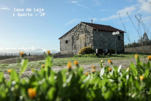 eine alte Scheune auf einem Feld mit Blumen in der Unterkunft Vila da Laje - Onde a Natureza o envolve - Serra da Estrela in Oliveira do Hospital