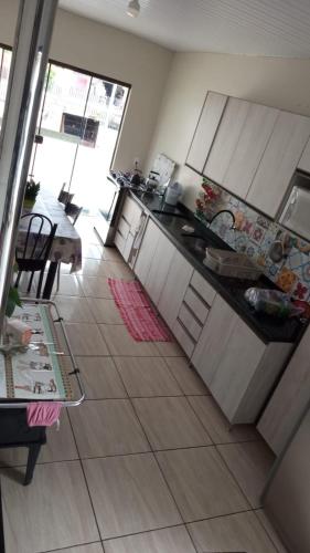 una cocina con armarios blancos y una mesa en una habitación en AMPLA CASA CONFORTAVEL NO GUARUJA CASCAVEL en Cascavel
