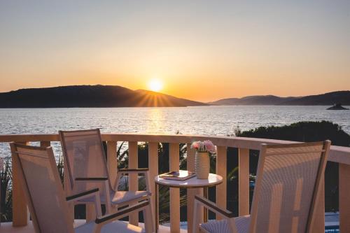 a table and chairs on a balcony with the sunset at Luxury Sunset Villa Trogir Private Beach in Okrug Donji