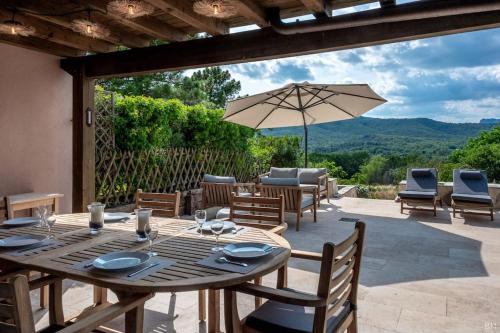 eine Terrasse mit einem Tisch, Stühlen und einem Sonnenschirm in der Unterkunft Esprit du Sud Les 4 Mousquetaires in Roquebrune-sur-Argens