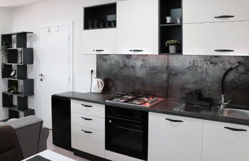 cocina con armarios blancos y fogones negros en Laganini, apartman 6 Tri Sky, en Nova Gradiška