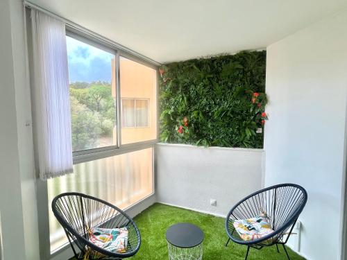 une chambre avec deux chaises et une grande fenêtre dans l'établissement Studio l'orée du bois AJACCIO, à Ajaccio
