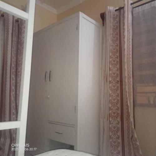 a white cabinet in a bedroom next to a window at Gever’s paradise in Watamu