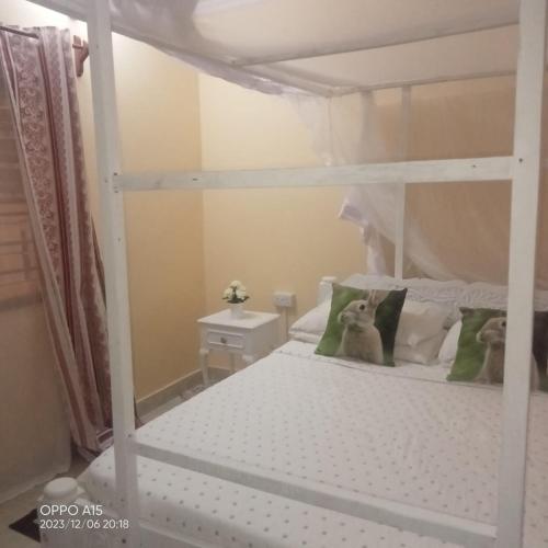 - une chambre avec des lits superposés blancs avec un chien assis dans l'établissement Gever’s paradise, à Watamu