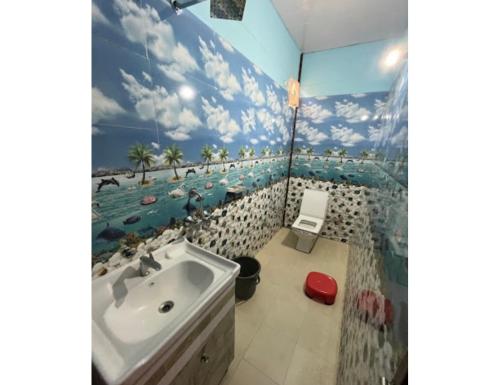 een badkamer met een wastafel en een muurschildering van een strand bij Hotel Vijaya, Dhar Gaon, Phata in Phata