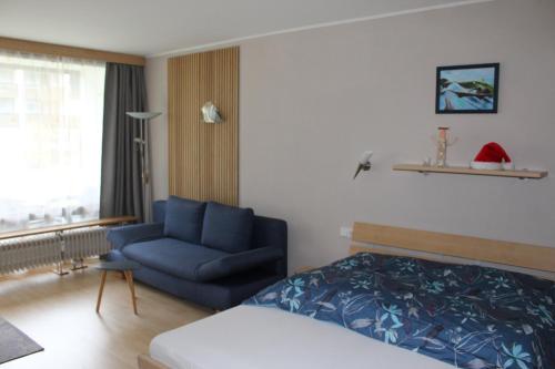 um quarto com uma cama e um sofá azul em Appartement 21 em Sankt Martin bei Lofer