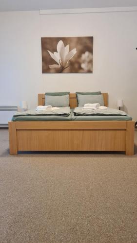 a wooden bed in a room with a painting on the wall at Penzion Dominik in Železná Ruda