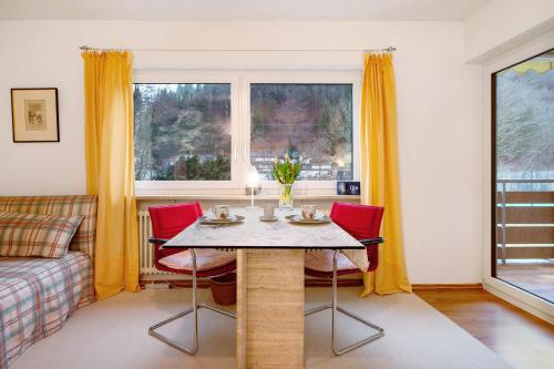 a living room with a table and red chairs at Eichhörnchens Paradies in Todtmoos