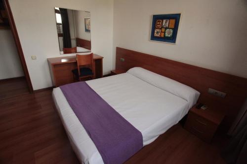 a bedroom with a white bed with a purple blanket at SunDos Feria Valencia in Valencia